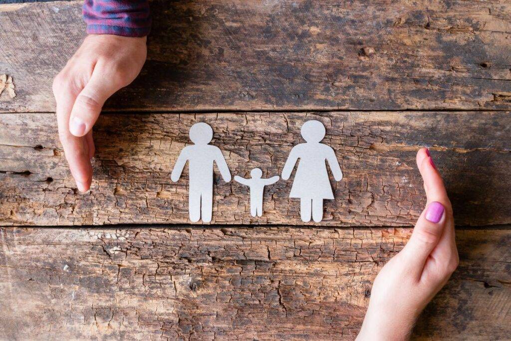 Paper dolls of a mom, dad and child lying on a table.