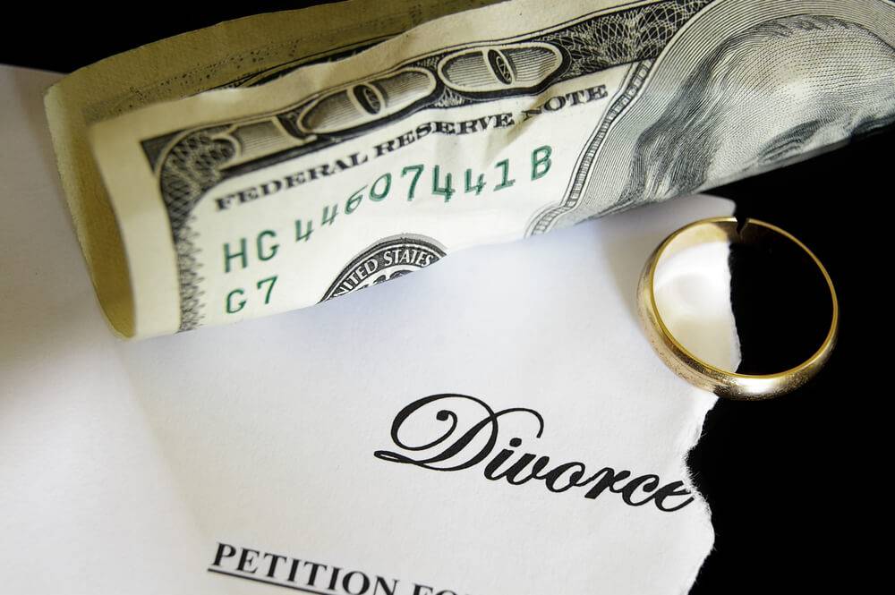 divorce petition paper with $100 bill and broken wedding ring