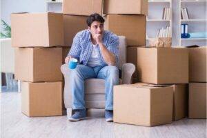 Man sitting in a house surrounded by packed boxes