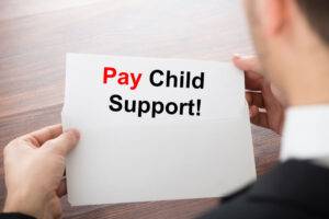 Man holding a piece of paper that says Pay Child Support.