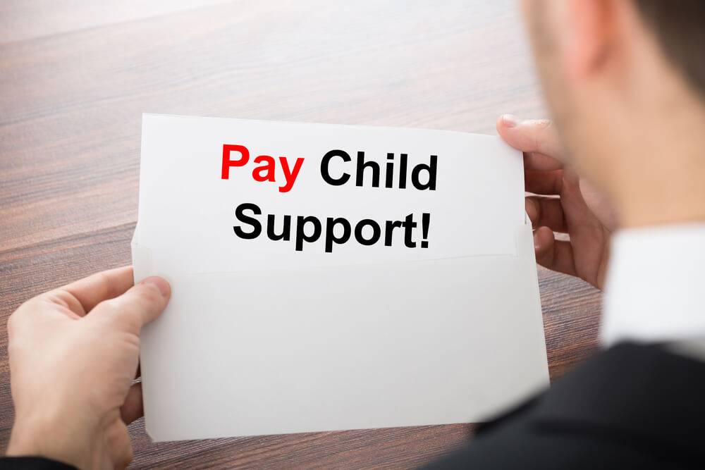 Man holding a piece of paper that says Pay Child Support.