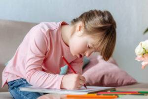 Girl with down syndrome writing on paper