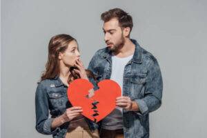 Man and women holding a paper heart that is ripped in half