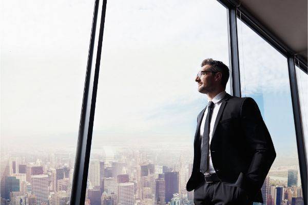 Man looking out office window that overlooks large city