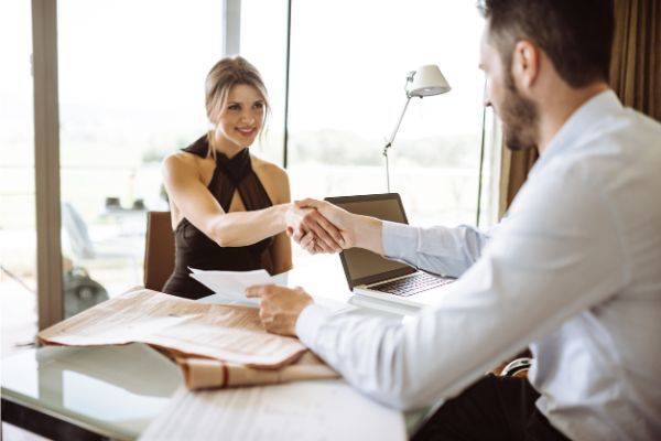 Man and woman sitting at a desk shaking hands