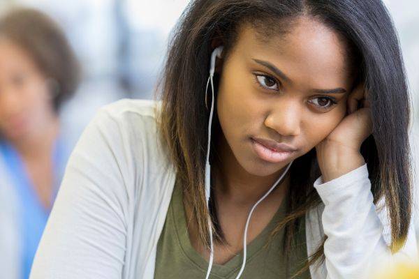 Young lady sitting listening to music while sad