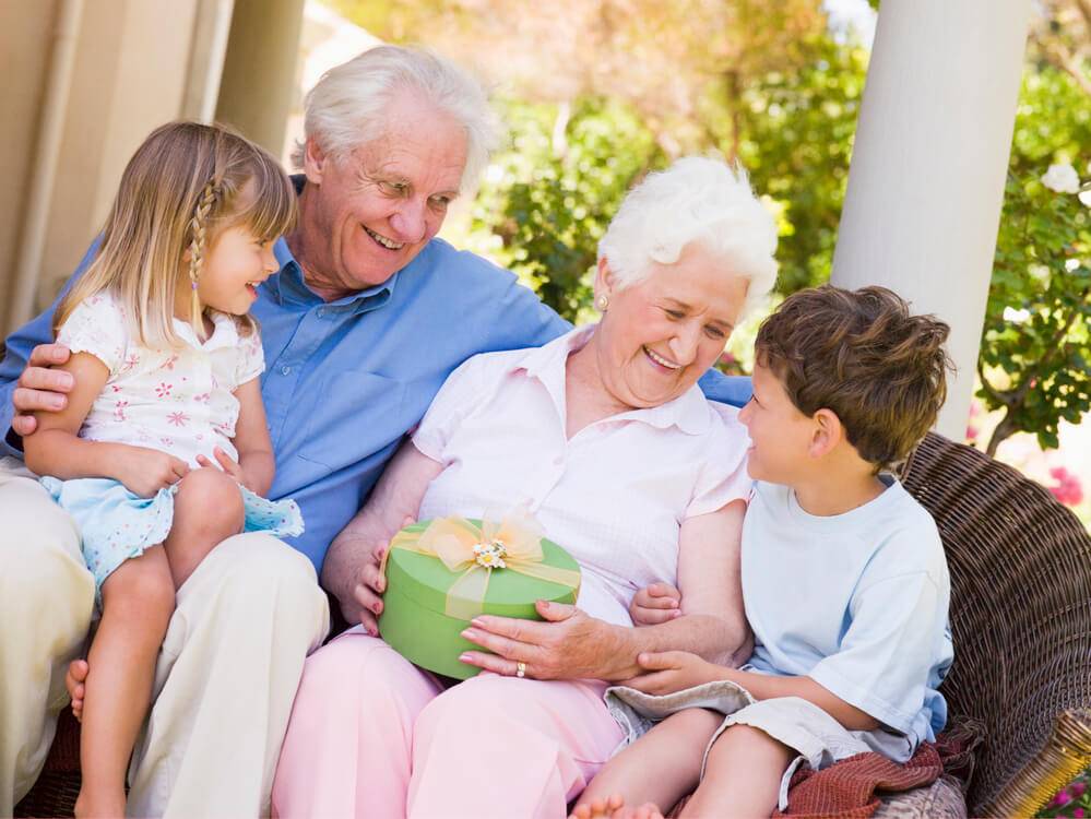 Grandparents sitting on the porch with their granddaughter and grandson