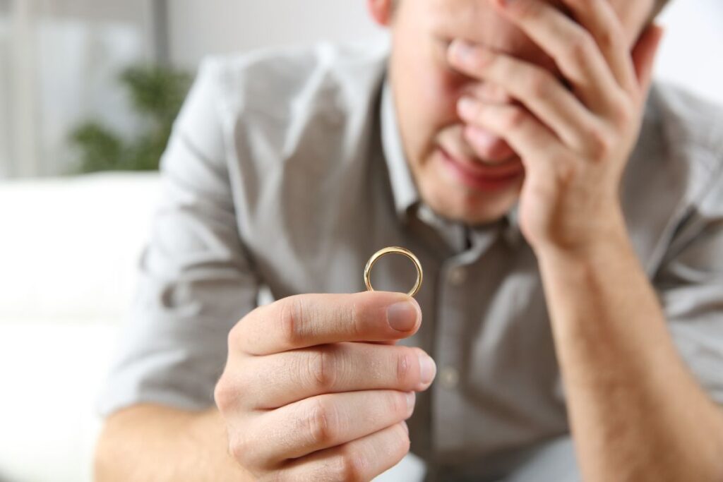 Man crying while holding wedding band.