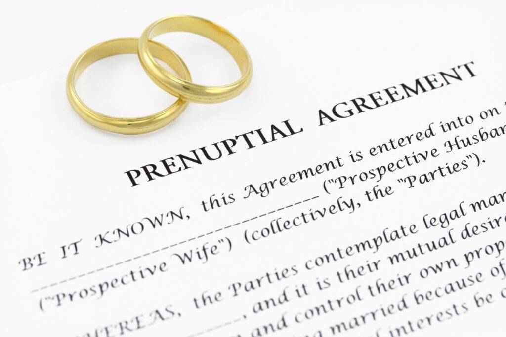 Prenuptial agreement written on paper with two gold rings on top.