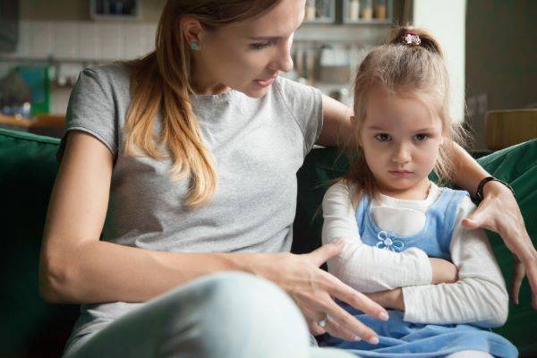 Mom talking with upset daughter while sitting on couch