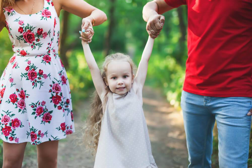 Mother and father walking holding hands with daughter