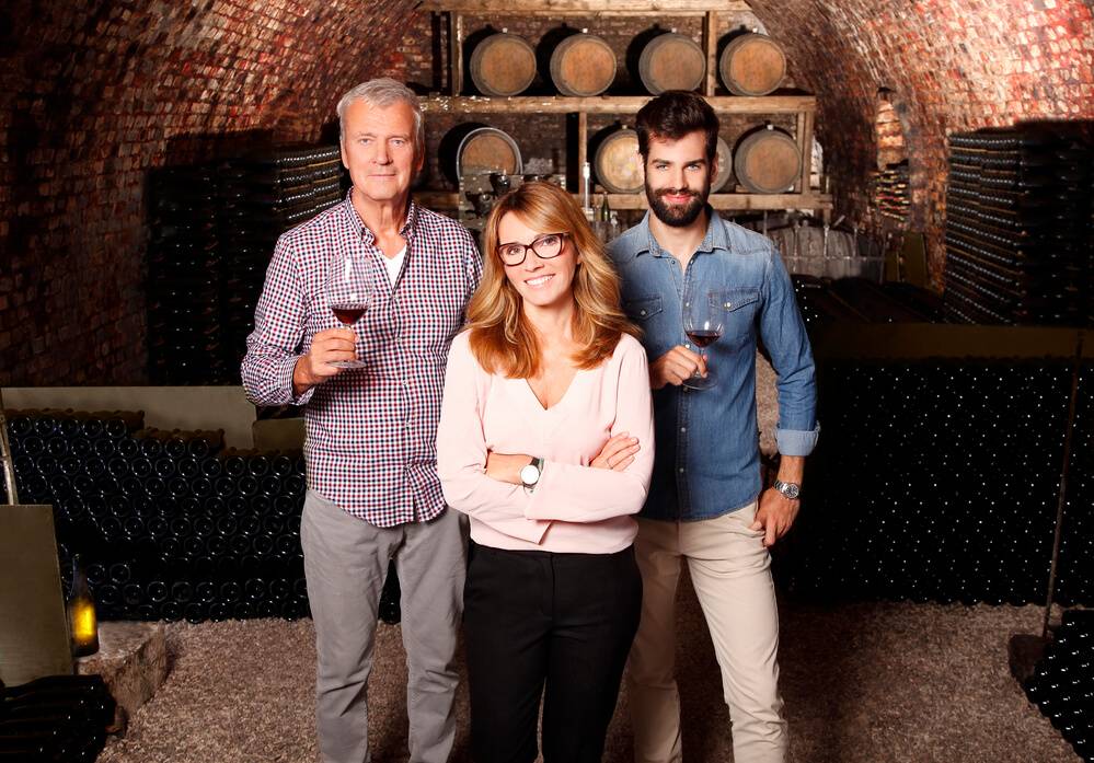 Family inside a wine cellar, holding wine glasses.