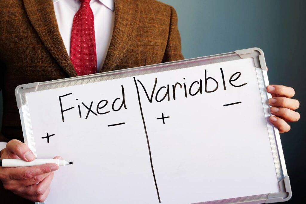 Man holding a white board. The words Fixed and Variable are written on the board.