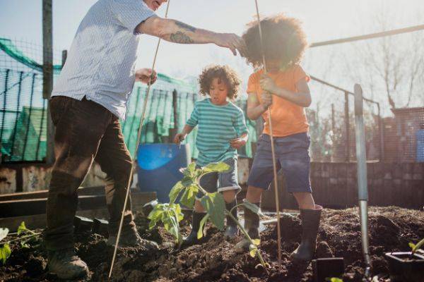 Children gardening with older man