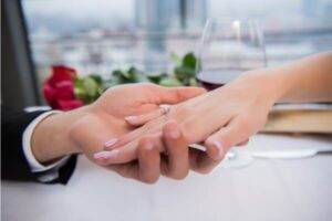 Man holding a women's hand with a engagement ring on her hand