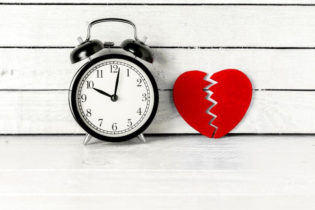 Clock sitting next to a ripped paper heart.