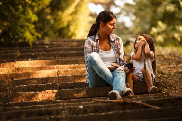 Mother sitting in a park with her daughter having a conversation