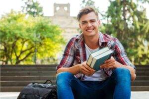 Young man holding books at college