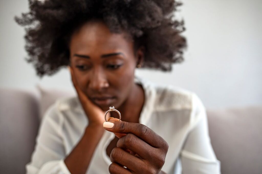 Sad woman holding a wedding ring up.