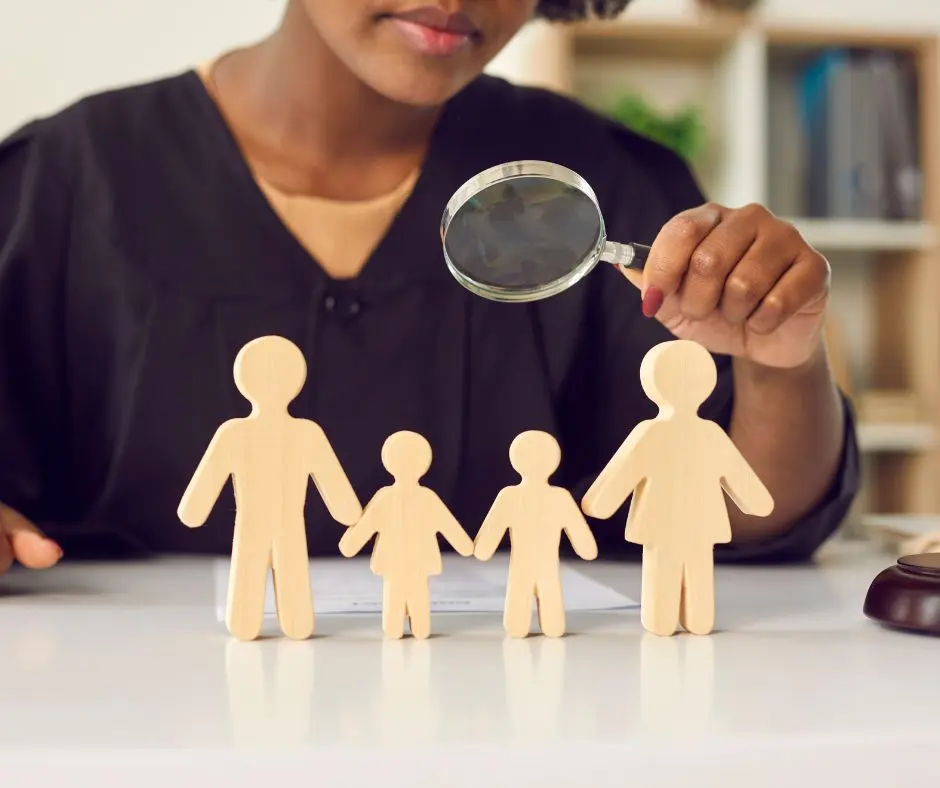 family law mediation: a mediator is holding a magnifying glass and looking at a miniature family
